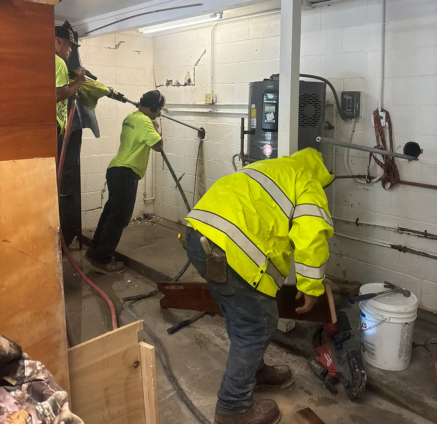 Team of workers drilling into basement wall to repair building foundation